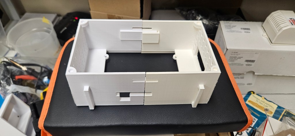 A white 3D printed box sits atop an orange and black case, showcasing its intricate details and design.